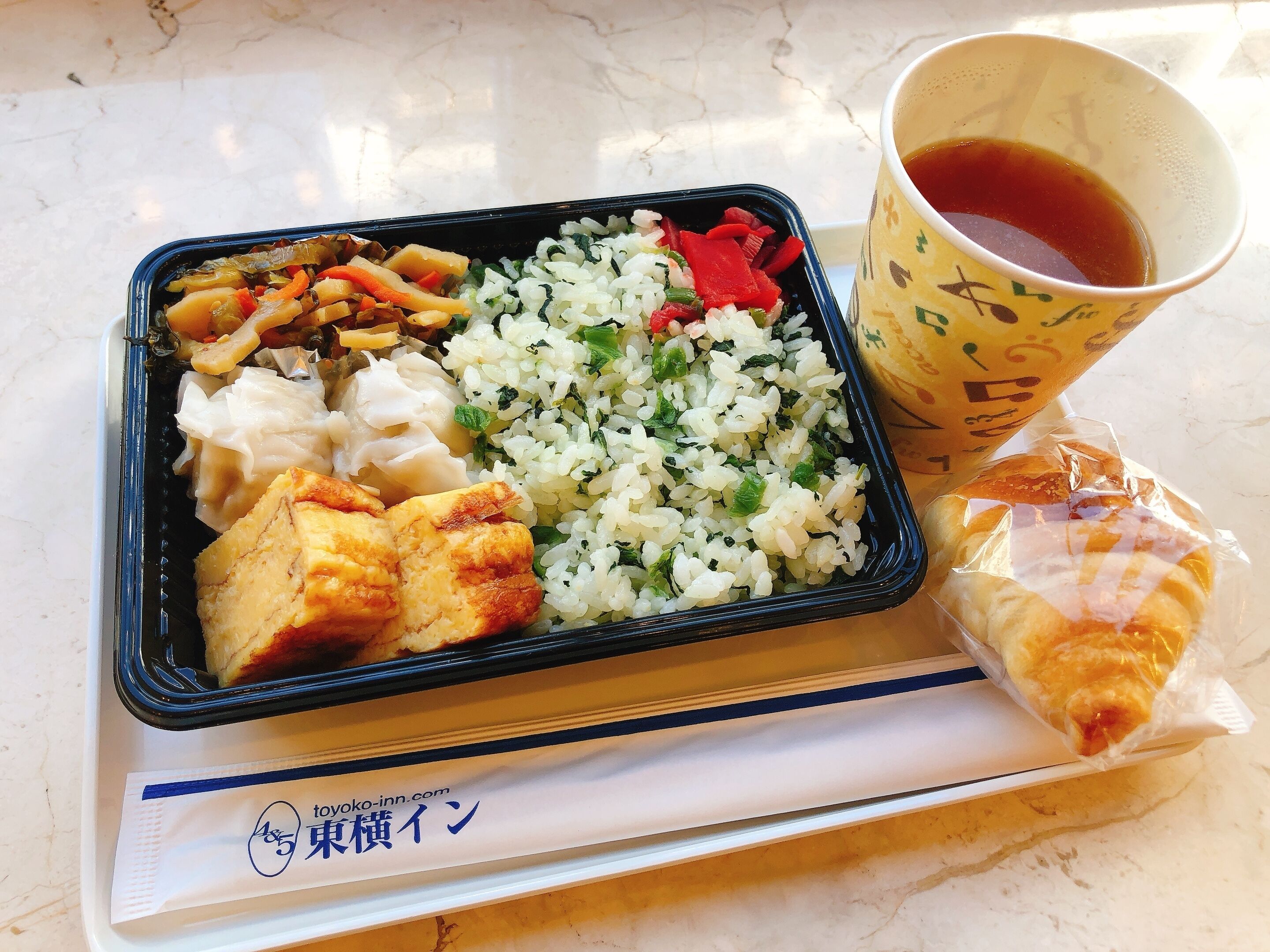 A meal consisting of rice, vegetables, tofu, and a pastry, served on a tray with a cup of tea.