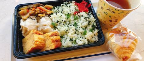 A meal consisting of rice, vegetables, tofu, and a pastry, served on a tray with a cup of tea.