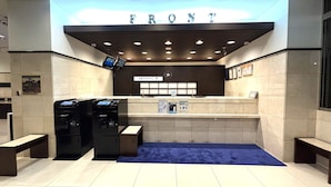 Un espace d’accueil avec une enseigne indiquant « ENTRÉE », un kiosque d’information numérique, une horloge et une moquette bleue.