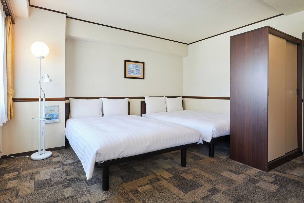 Une chambre d’hôtel avec un lit, une lampe de chevet et un tableau encadré au mur.