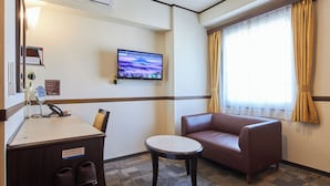 A hotel room with a desk, a chair, a sofa, a TV mounted on the wall, and a window with curtains. - Toyoko Inn Chiba Station Higashi (Chiba)