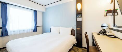 Una habitación de hotel con una cama grande, un escritorio con teléfono y un espejo.