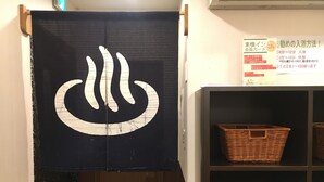 A room with a dark curtain featuring a white symbol, wooden shelves with wicker baskets, and a wall with a sign in Japanese.