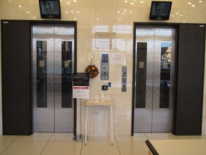 An elevator area with two elevators, a small table with a bottle, and a sign with instructions. - Toyoko Inn Gumma Ota Station Minami (Ota)