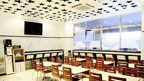 Una aula amb files de taules i cadires, una pantalla de projector i una finestra amb vista a l'exterior.