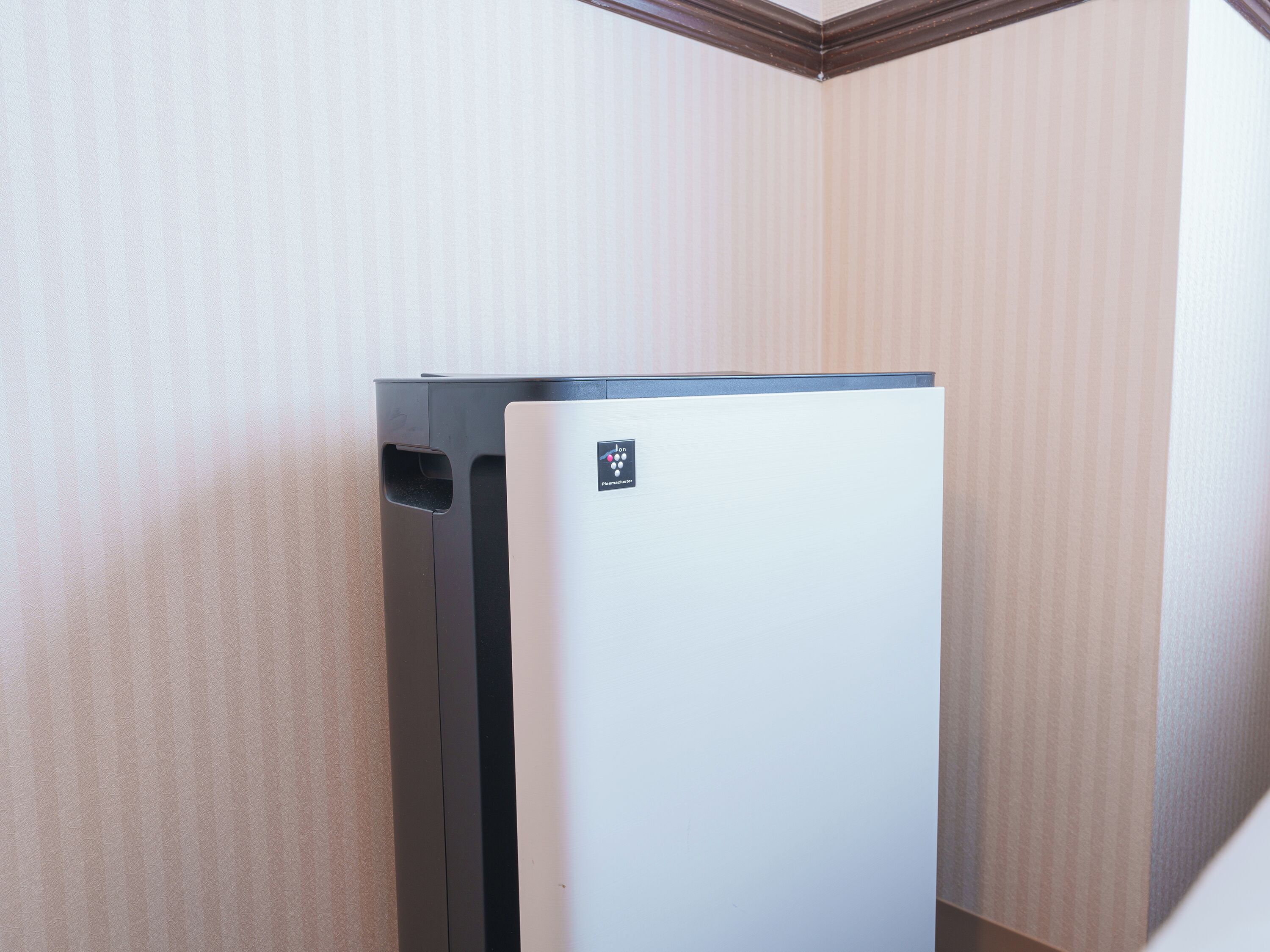 A corner of a room with a white refrigerator and a wall with vertical stripes.