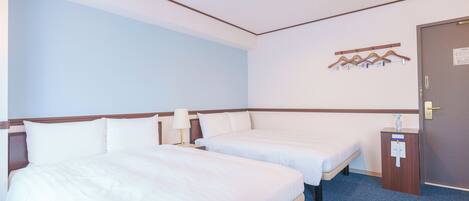 Habitación de hotel con dos camas, alfombra azul, puerta de madera y perchero en la pared.