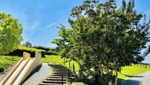 A park with a concrete slide, a paved path, and a large tree. - Toyoko Inn Osaka Itami Kuko (Toyonaka)