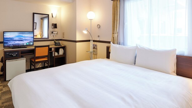 A hotel room with a bed, a desk with a computer, a coffee maker, a lamp, and a window with curtains. - Toyoko Inn Osaka Itami Kuko (Toyonaka)