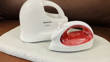 A white Panasonic iron with a red water tank on a white cushion on a brown leather couch.