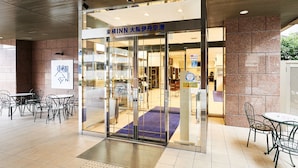 A hotel entrance with a glass door, a signboard, and a tiled floor. - Toyoko Inn Osaka Itami Kuko (Toyonaka)