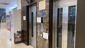 An elevator area with marble walls, a digital screen, and informational signs. - Toyoko Inn Osaka Itami Kuko (Toyonaka)