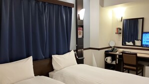 Une chambre d’hôtel avec deux lits, un bureau, une chaise, un ordinateur et un miroir.