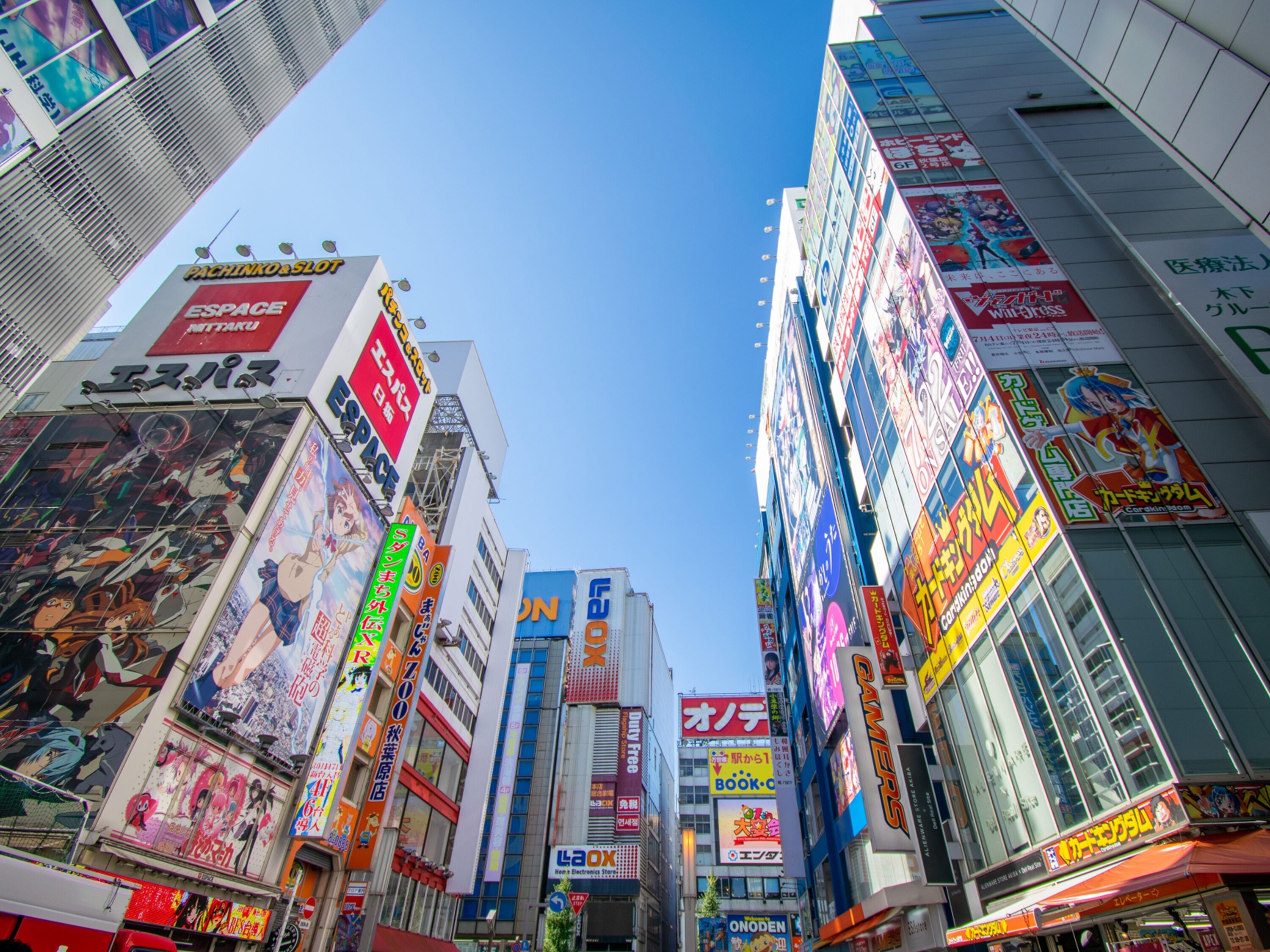 A bustling urban street with tall buildings adorned with various colorful advertisements and signs.