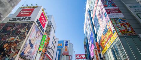A bustling urban street with tall buildings adorned with various colorful advertisements and signs.