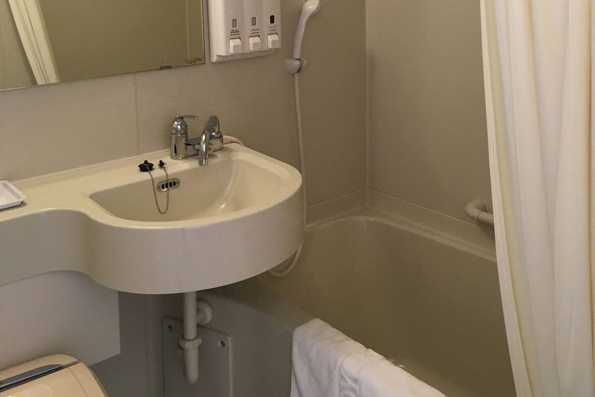 Une salle de bain équipée d’un lavabo, d’un robinet et d’une douchette à main.