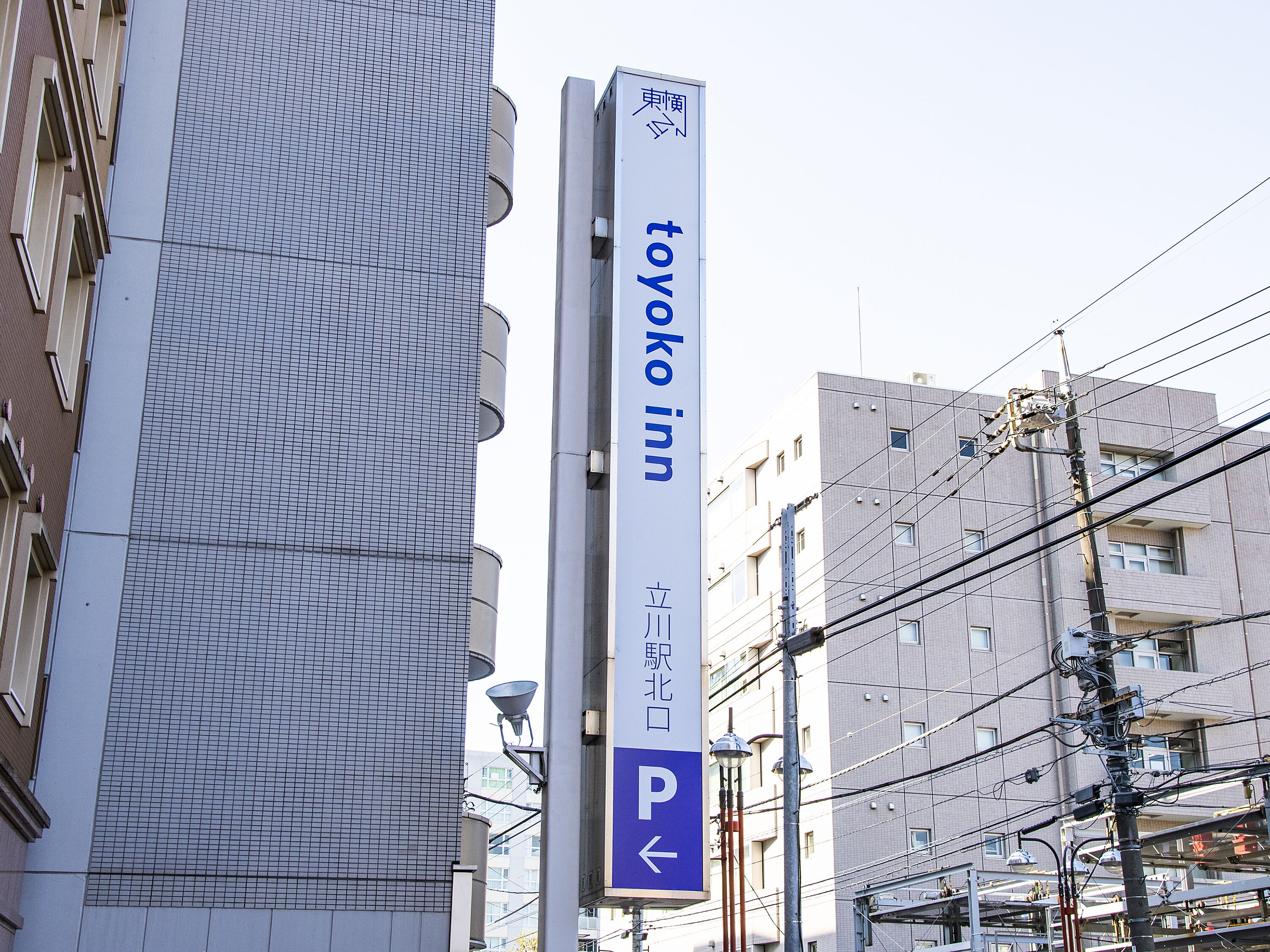 Un edificio alto con un letrero de 'Toyoko Inn' y una señal de indicaciones para el estacionamiento.