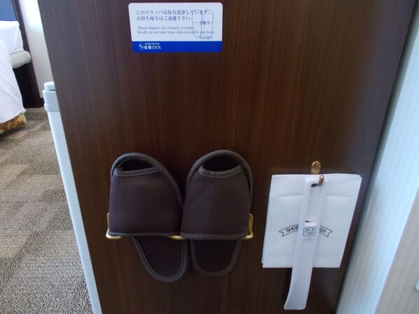 A pair of slippers on a shoe rack and a note on the door.