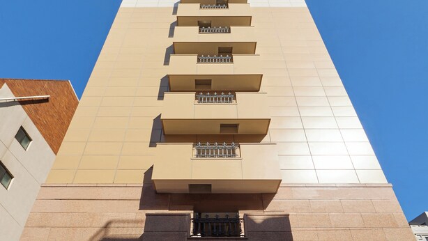 Ein hohes Gebäude mit einer beige farbenen Fassade und mehreren Balkonen.