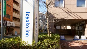 Ein Schild des Toyoko Inn mit freiem Blick auf den Eingangsbereich und die Umgebung des Hotels.