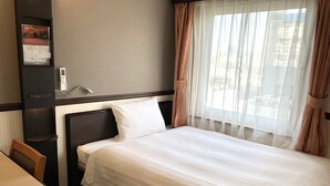 Ein Hotelzimmer mit Bett, Schreibtisch und Stuhl.