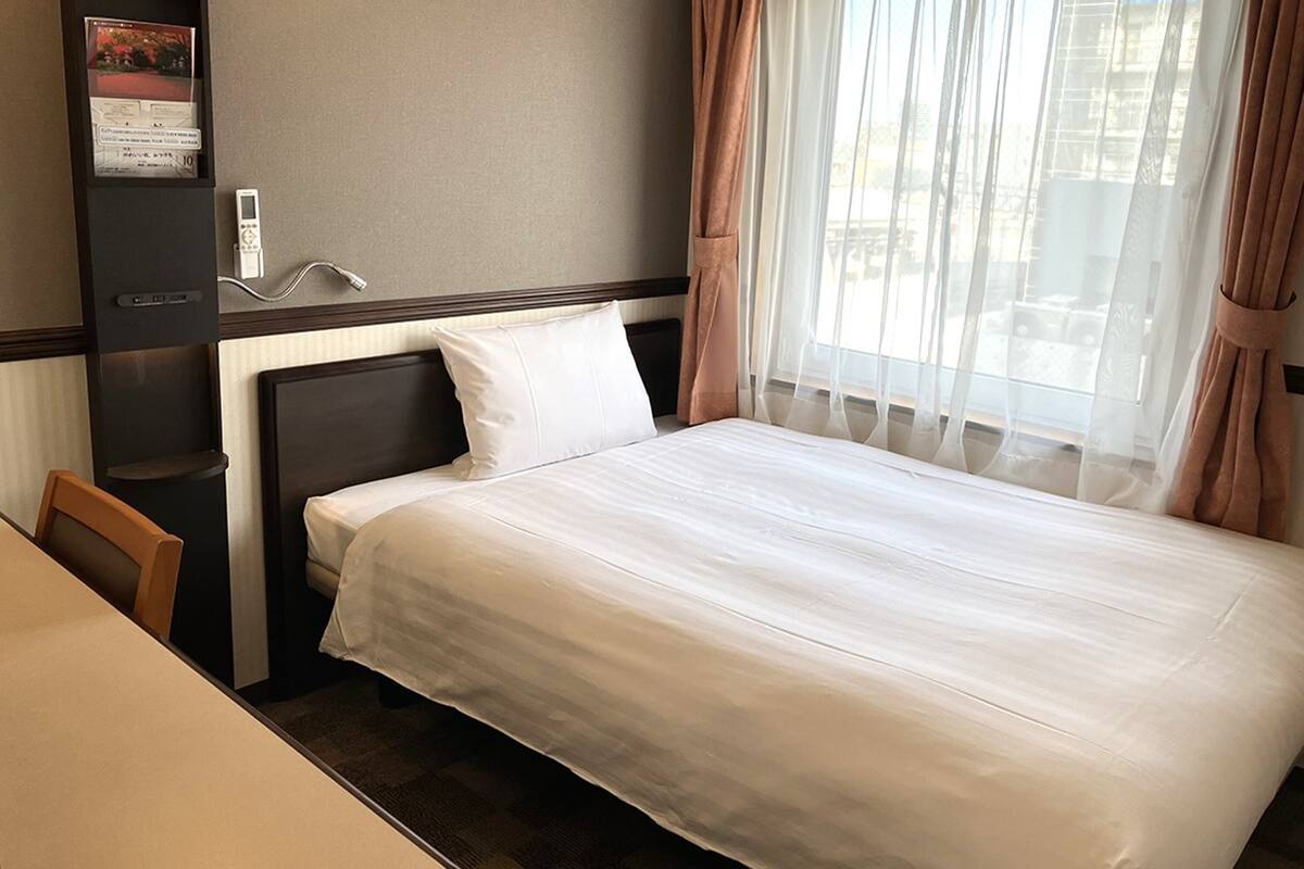 Ein Hotelzimmer mit Bett, Schreibtisch und Stuhl.