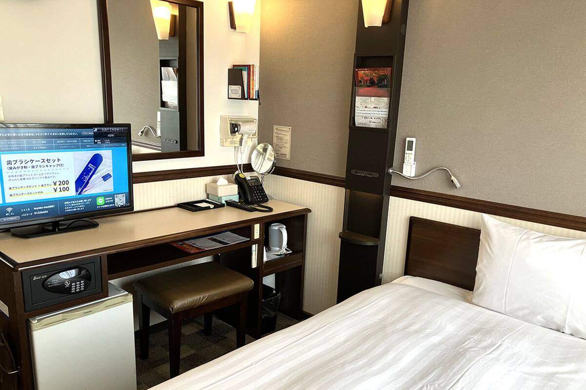 Ein Hotelzimmer mit Bett, Schreibtisch, Stuhl und einem kleinen Kühlschrank.