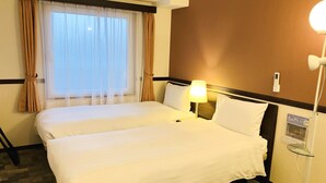 Een hotelkamer met twee bedden, een nachtkastje, een lamp en een aan de muur bevestigde televisie.