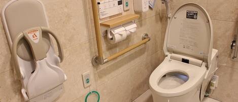 A modern bathroom with a toilet, bidet, and hand dryer.