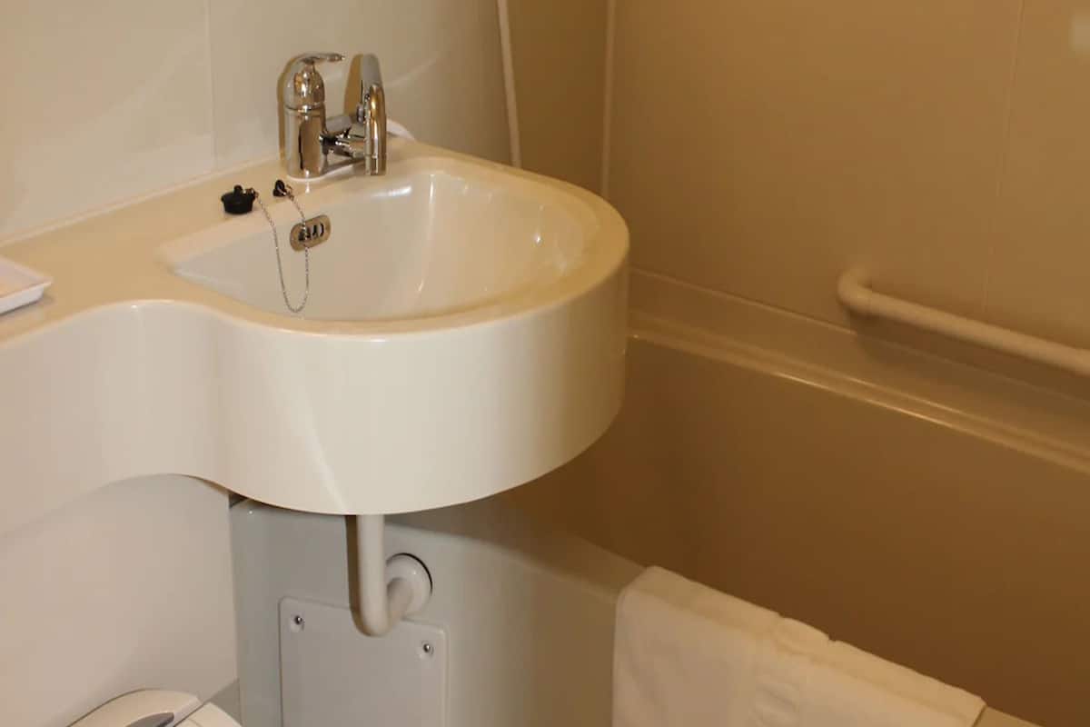 Une salle de bain avec un lavabo blanc, un porte-serviettes et des toilettes.