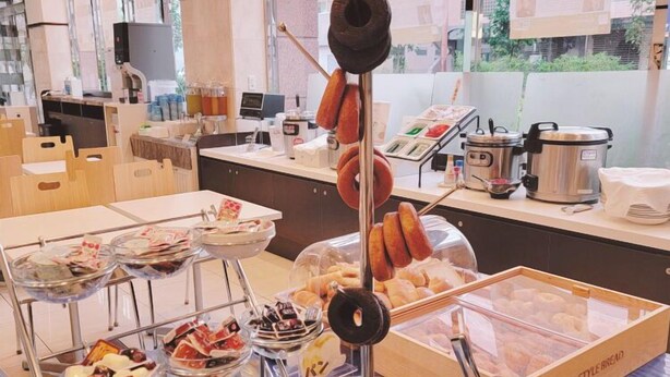 Montaje de bufé con diversos alimentos, incluyendo rosquillas, pasteles y una variedad de postres.