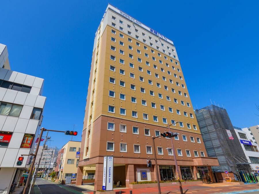 Un hotel de varios pisos con fachada amarilla y marrón, numerosas ventanas y un letrero que indica que es un Toyoko Inn.
