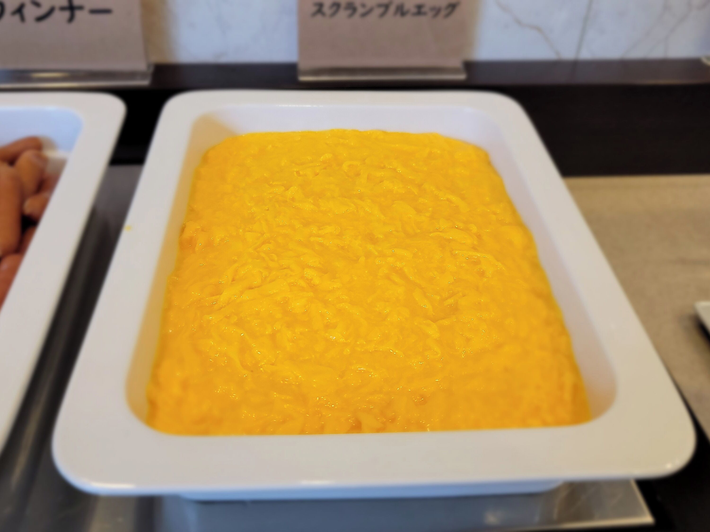 A white rectangular dish filled with a yellowish food item, possibly a dip or spread, on a table.