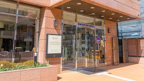 Entrada de un edificio con puerta de vidrio, un cartel sobre la puerta y un letrero pequeño a la izquierda.