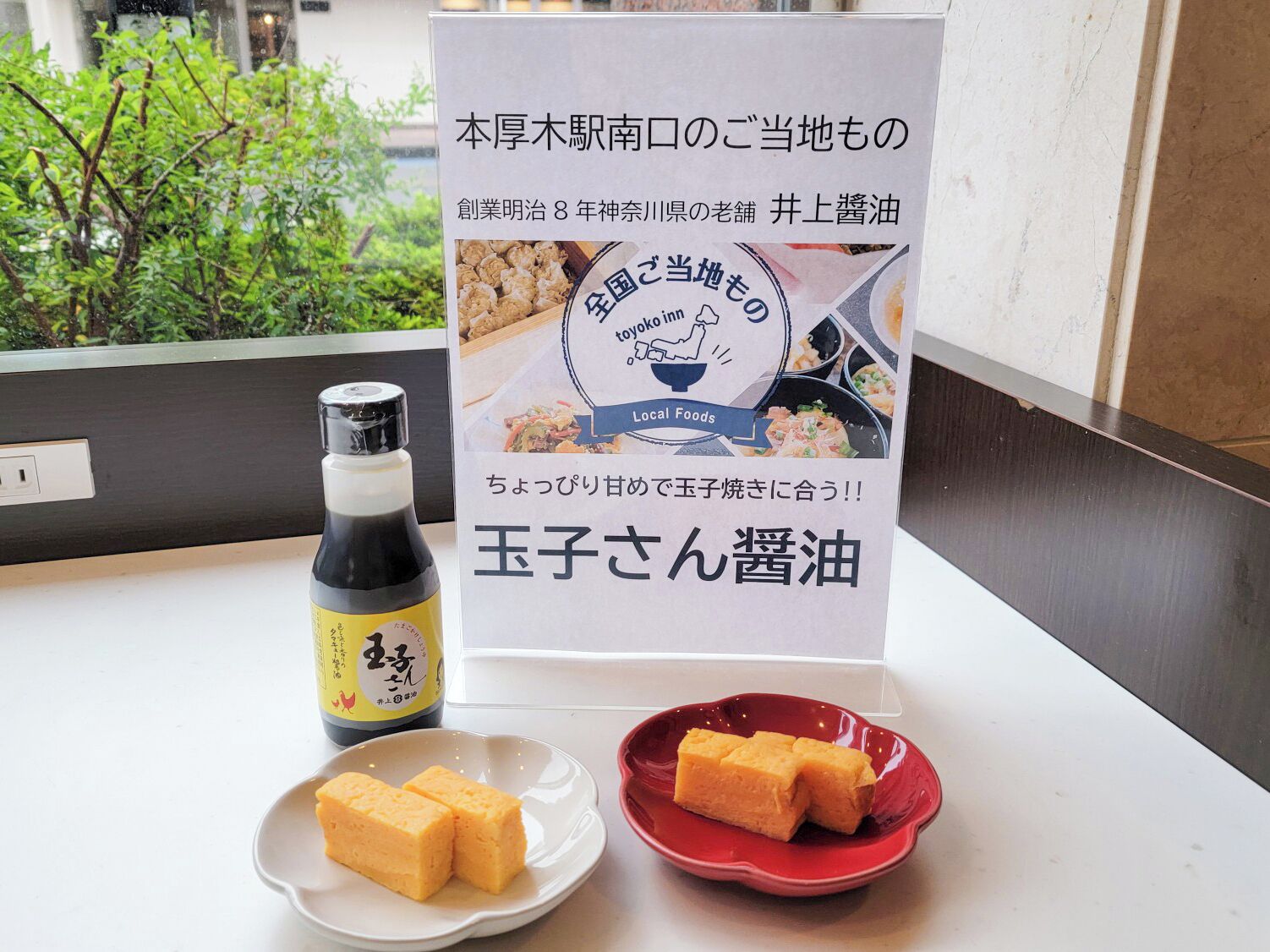 Une table avec une bouteille de sauce soja, une enseigne avec du texte en japonais et deux assiettes contenant des cubes de tofu.