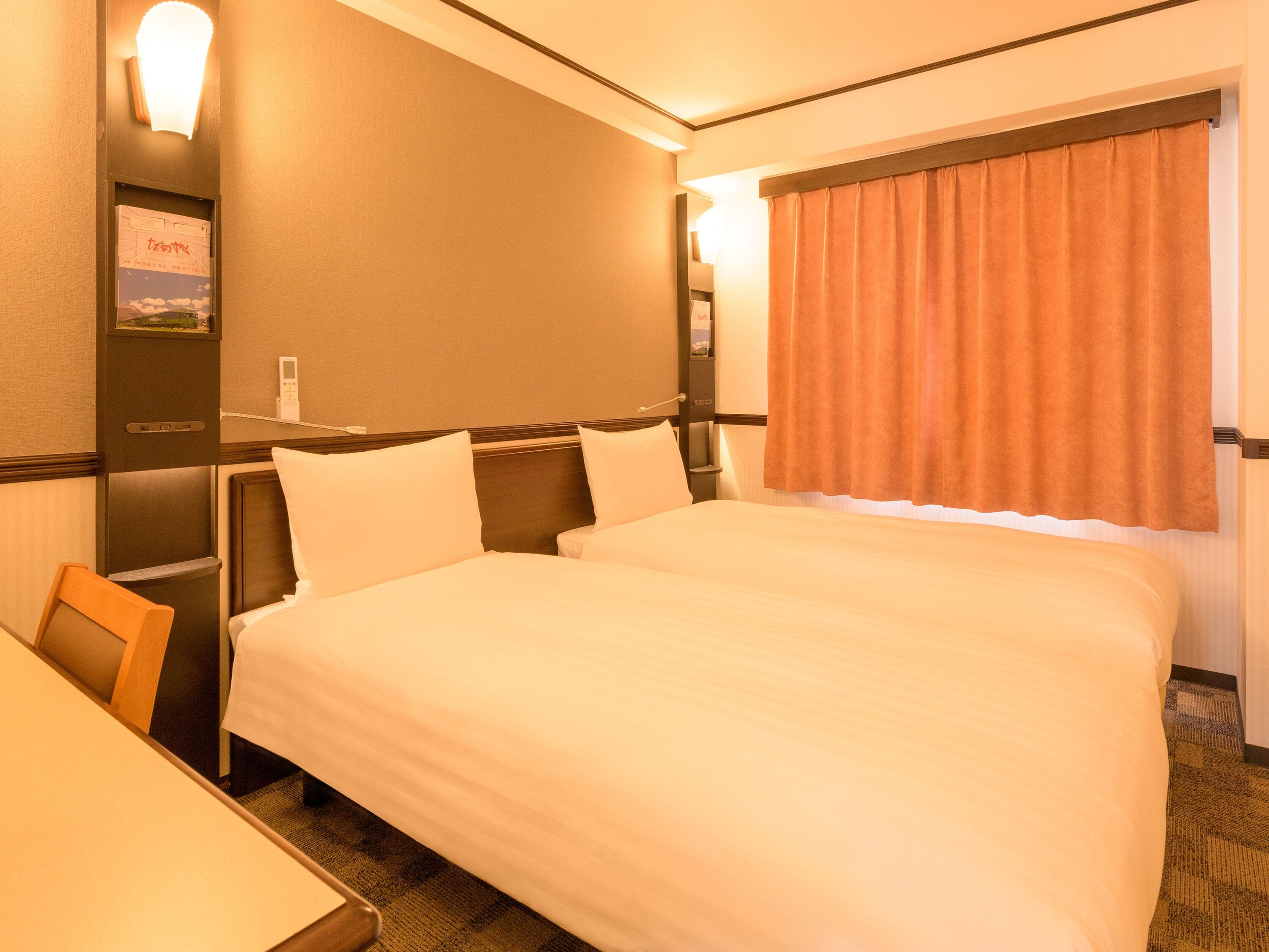 A hotel room with a large bed, a desk, and a window with curtains.