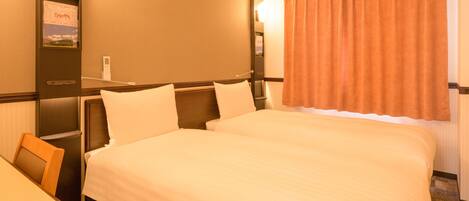 A hotel room with a large bed, a desk, and a window with curtains.