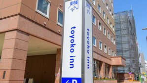 Señal de hotel con la inscripción 'Toyo Ko Inn' y flechas direccionales.