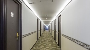 A hotel hallway with carpeted floors, doors on both sides, and a light-colored wall with a decorative border. - Toyoko Inn Kintetsu Nara Ekimae (Nara)