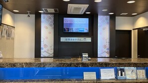 A hotel reception desk with a digital screen displaying information, a blue counter, and a sign indicating a hotel room. - Toyoko Inn Kintetsu Nara Ekimae (Nara)
