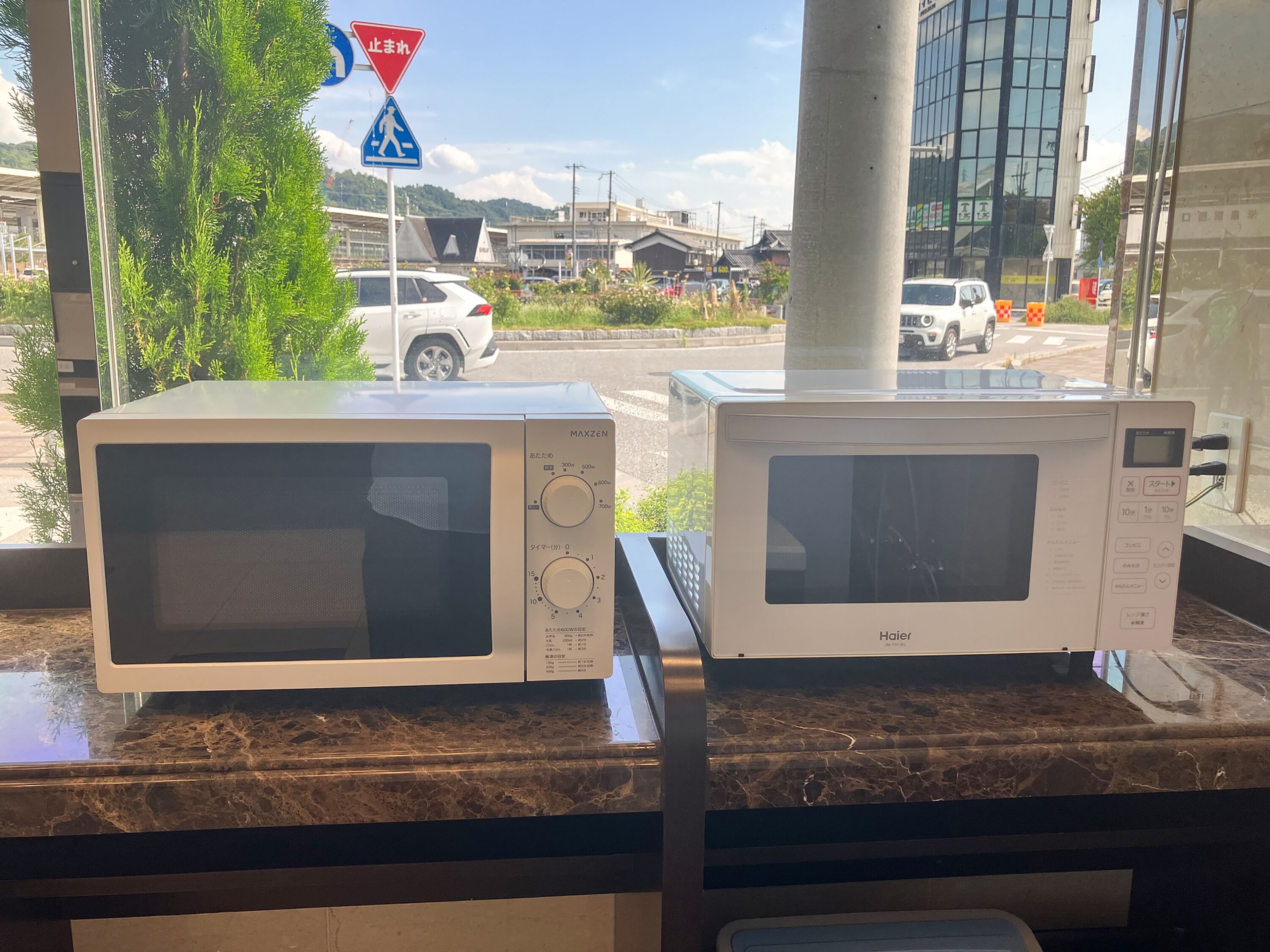 Two white MAXZEN brand microwaves on a marble countertop.