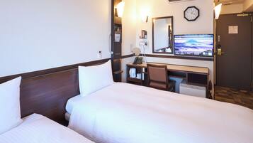 A hotel room with two beds, a desk, a chair, a desk lamp, a clock, and a television.