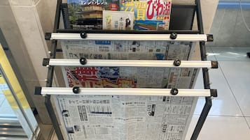 A rack with various Japanese newspapers and a tourist guidebook.