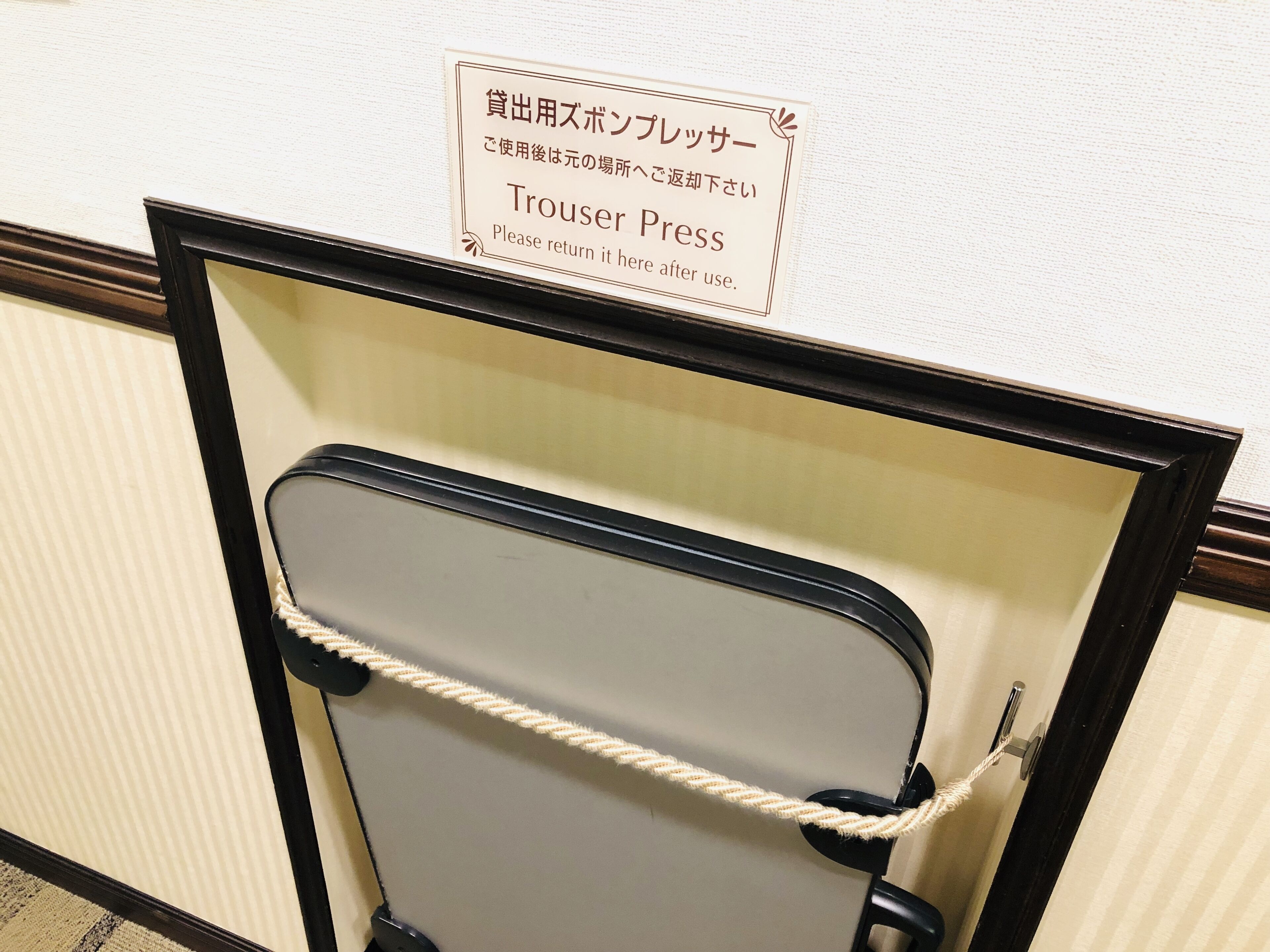 A trouser press with a sign above it in both Japanese and English.