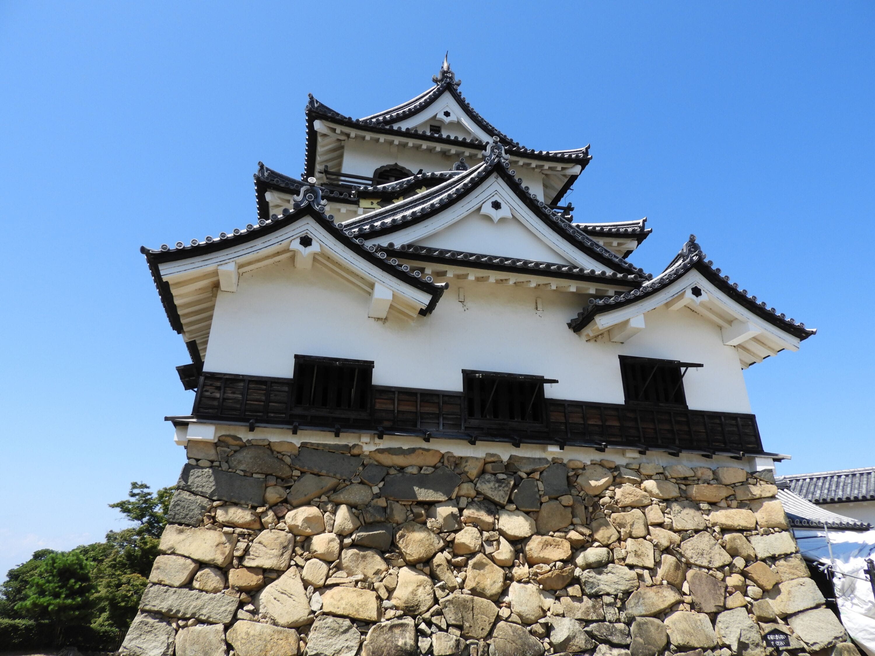 A traditional Japanese castle with multiple tiers and a stone base.