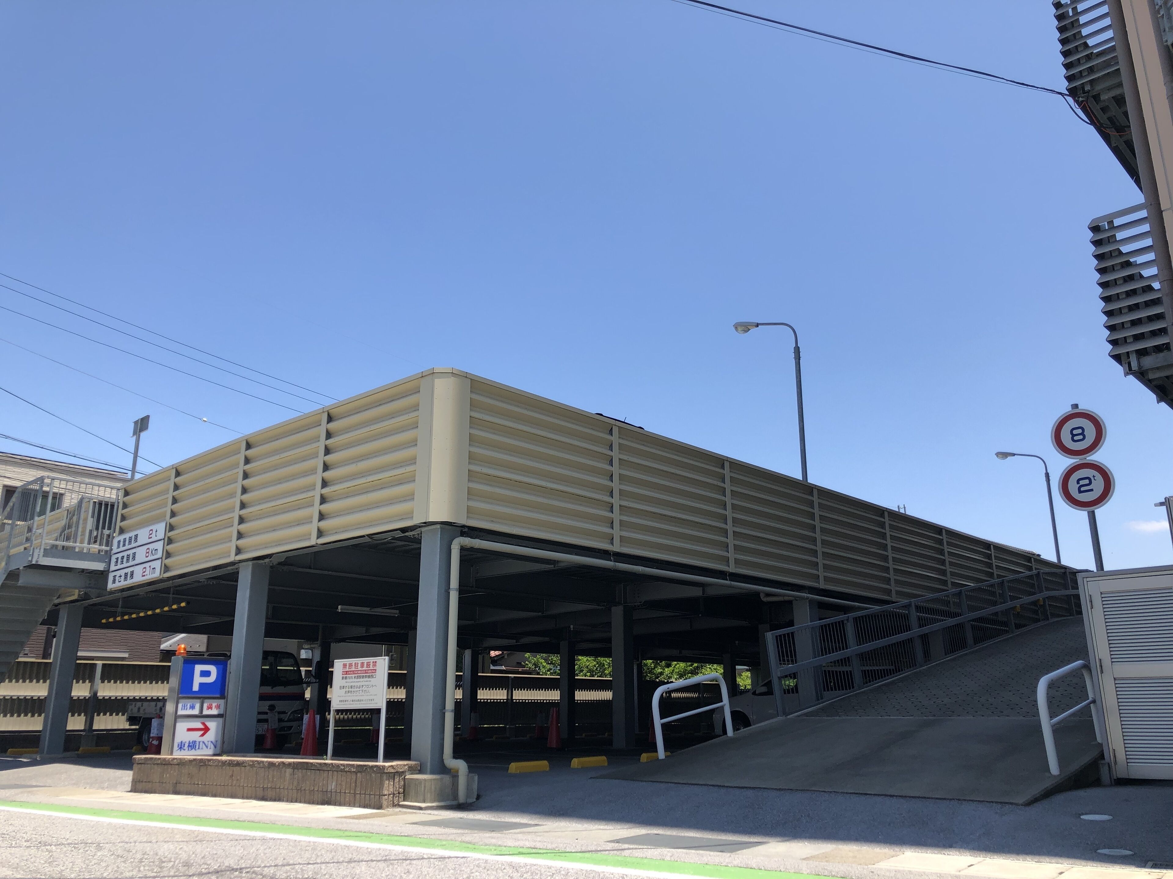 Una estructura de estacionamiento techada con una rampa que lleva a la entrada de un edificio.