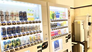 Vending machines stocked with beverages and snacks in a hotel setting.