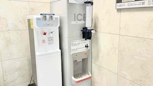 A water dispenser with a push button, a water bottle, and a sign with instructions.