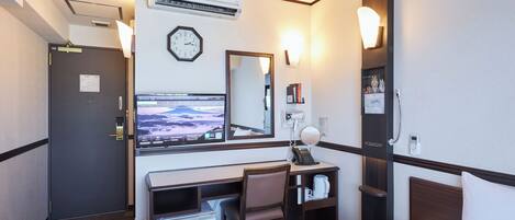 Habitación de hotel con cama, escritorio, silla y televisor que muestra un paisaje montañoso.