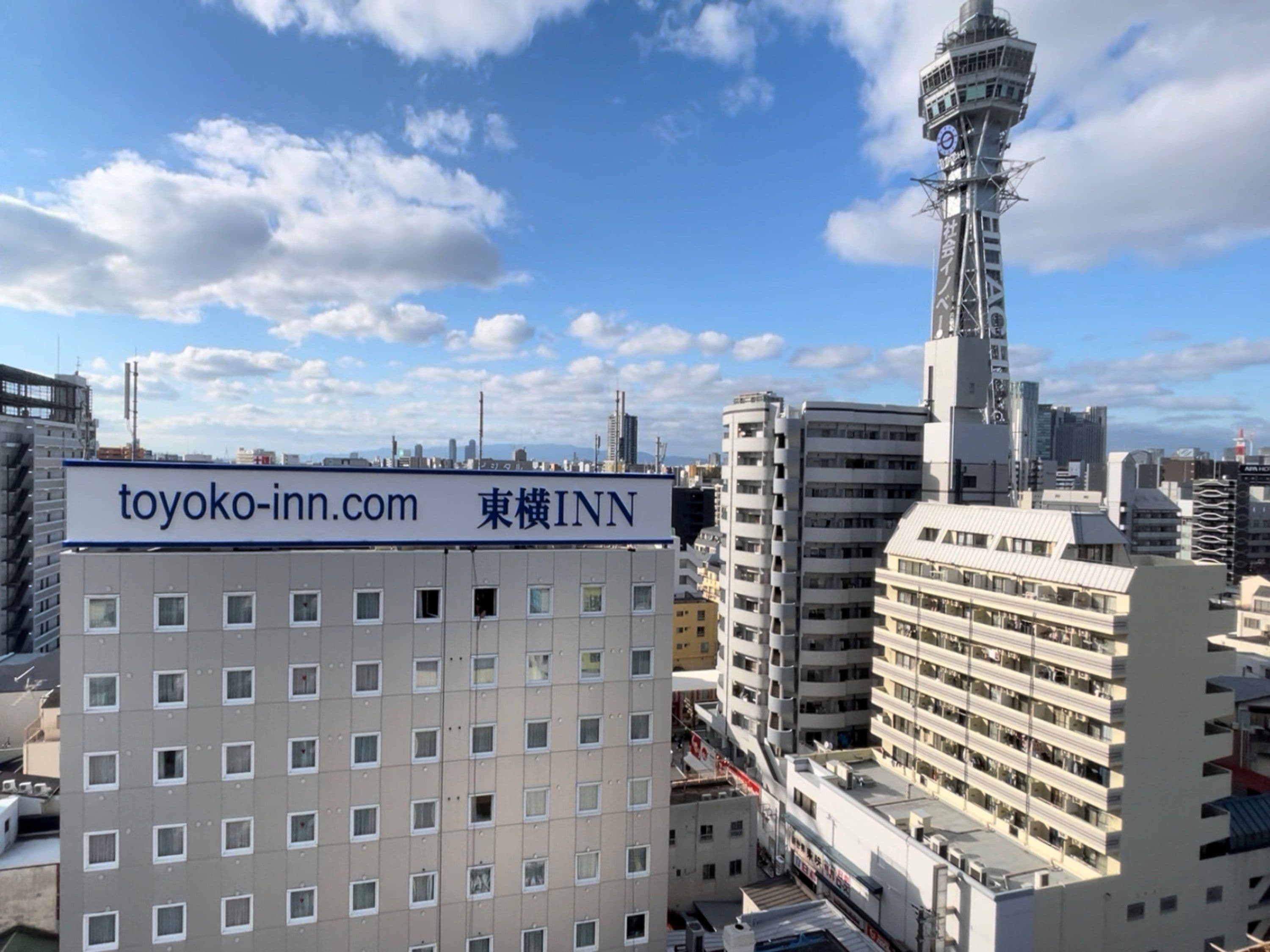 A multi-story building with a sign for 'toyoko-inn.com' and '東横INN' indicating it is part of the Toyoko Inn chain.